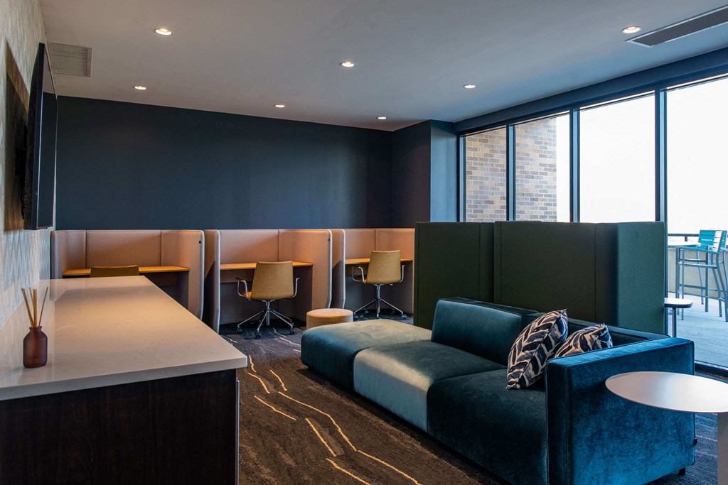 large couch in front of a wall mounted tv with chairs and desks behind it at The Apex at CityPlace, Overland Park, KS, 66210