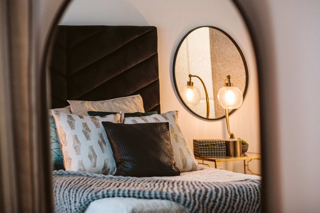 reflection of a bed and nightstand in a large mirror at The Apex at CityPlace, Overland Park, Kansas