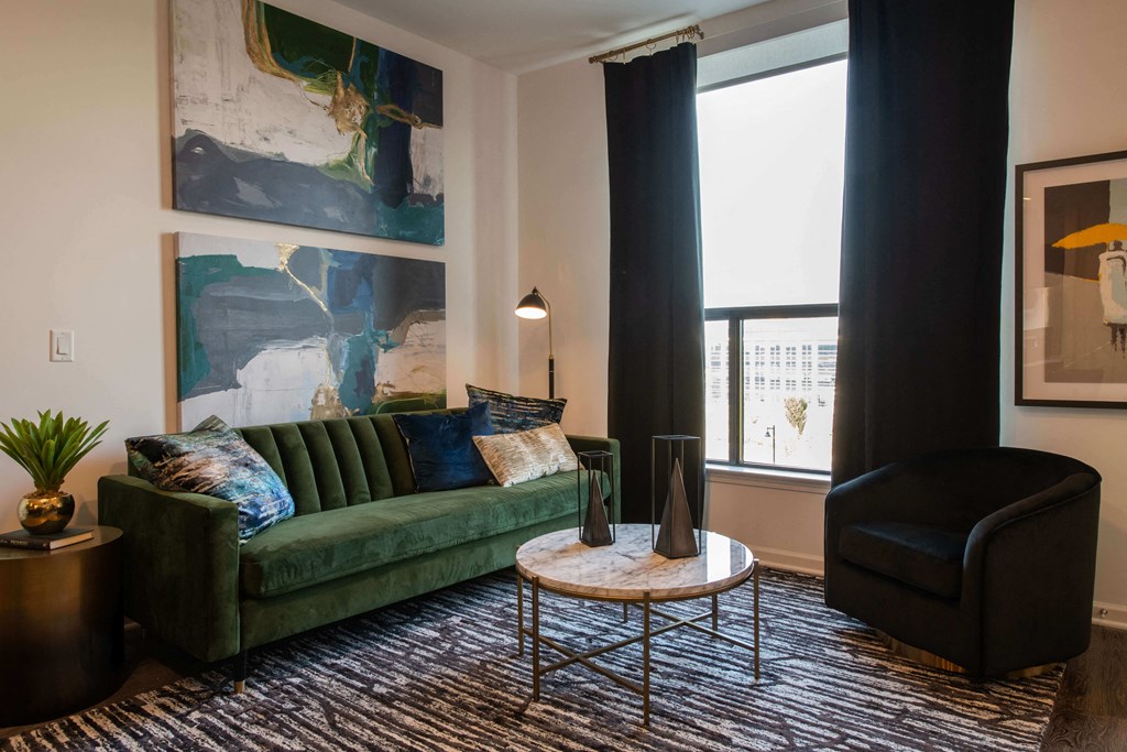 sitting area with a large green couch, small black chair, coffee table, and black curtains at The Apex at CityPlace, Overland Park, KS, 66210