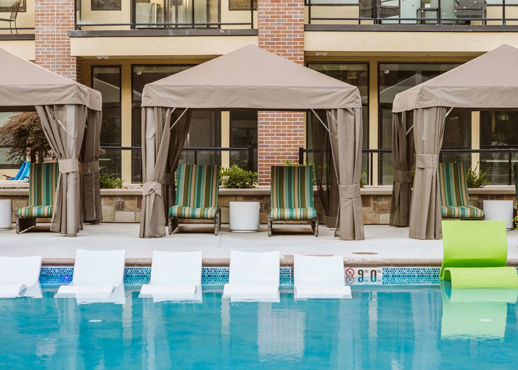 chaise lounge chairs under a canopy by an outdoor pool at The Apex at CityPlace, Overland Park, KS