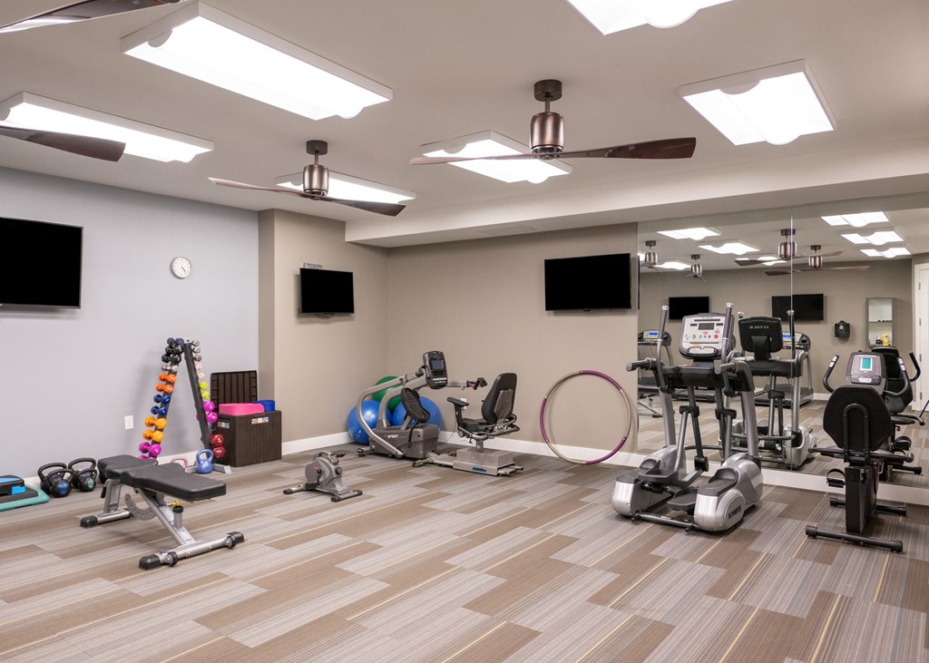 A gym with weights and cardio equipment at Aspen Ridge 55+ Active Adult Community