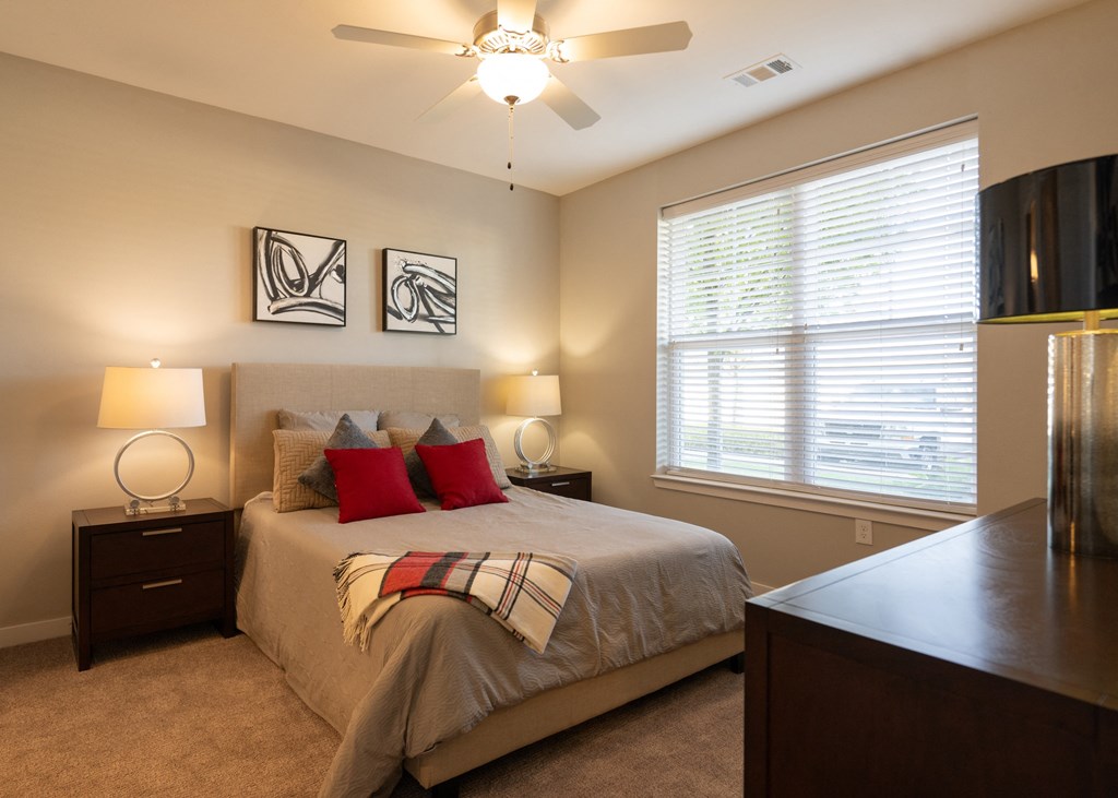 A furnished bedroom with a ceiling fan and a window at Aspen Ridge 55+ Apartment Community in Olathe, KS