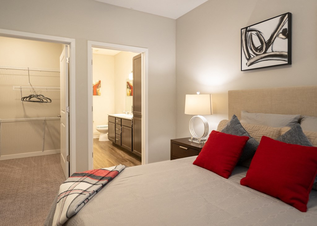 A furnished bedroom with a full bathroom and walk-in closet at Aspen Ridge 55+ Apartment Community in Olathe, KS