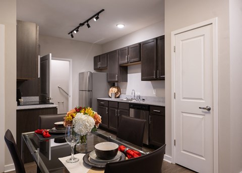 a kitchen and dining room with dark cabinets and a table and chairs