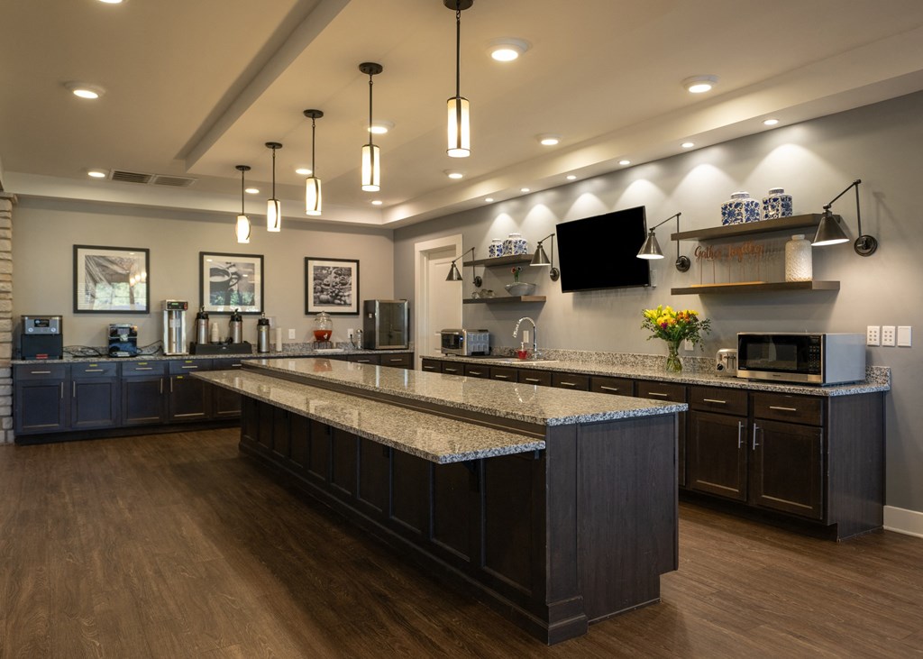 Community kitchen with granite counter tops and a tv at Aspen Ridge 55+ Active Adult Community