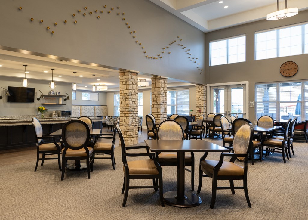 Dining hall with tables and chairs and a kitchen at Aspen Ridge 55+ Active Adult Community