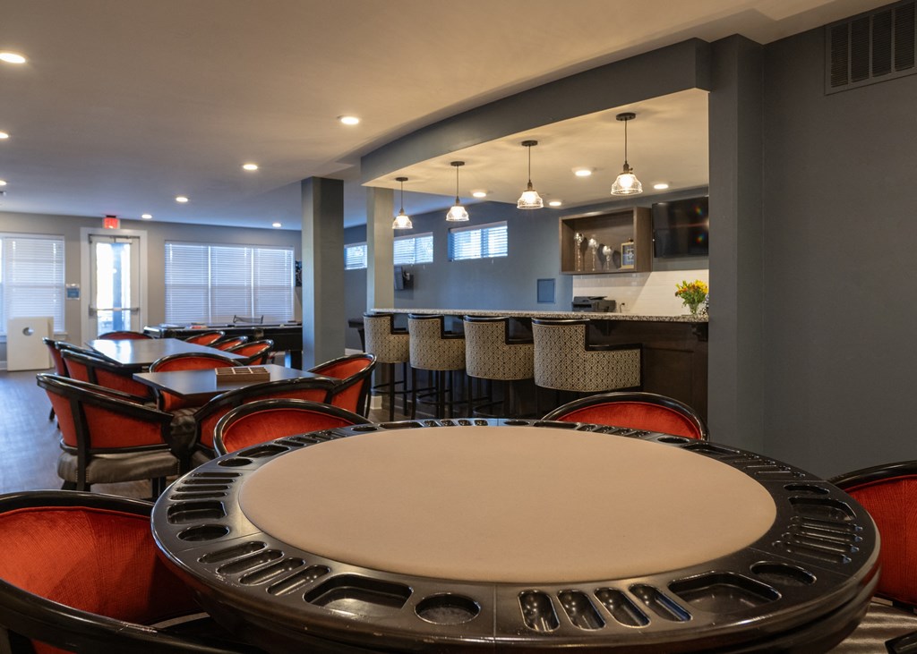 A clubhouse lounge with tables, chairs, and a bar top at Aspen Ridge 55+ Active Adult Community