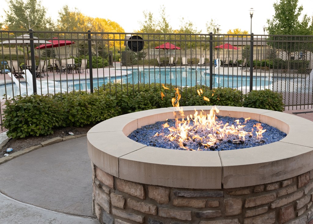 An outdoor fire pit in front of a swimming pool at Aspen Ridge 55+ Active Adult Community