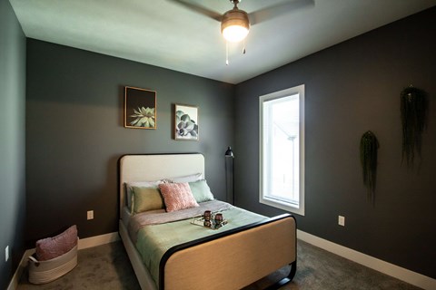 A bedroom with a bed, a ceiling fan, and two wall art pieces.