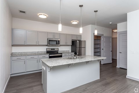 A modern kitchen with a granite countertop and stainless steel appliances.