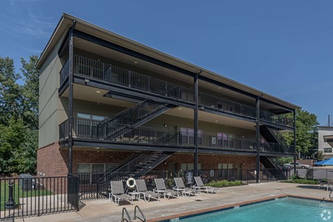 A modern building with a pool and lounge chairs.