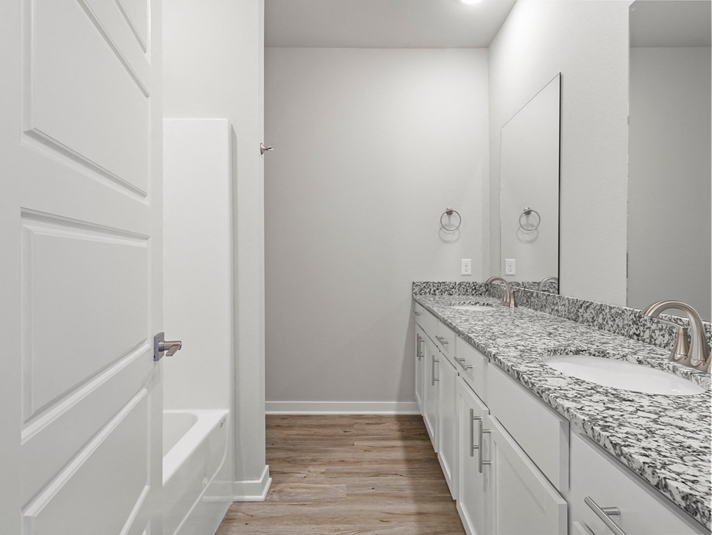 a bathroom with white cabinets and granite counter tops and a bath tub and a sink at Hillcrest Village, Springdale, AR 72762