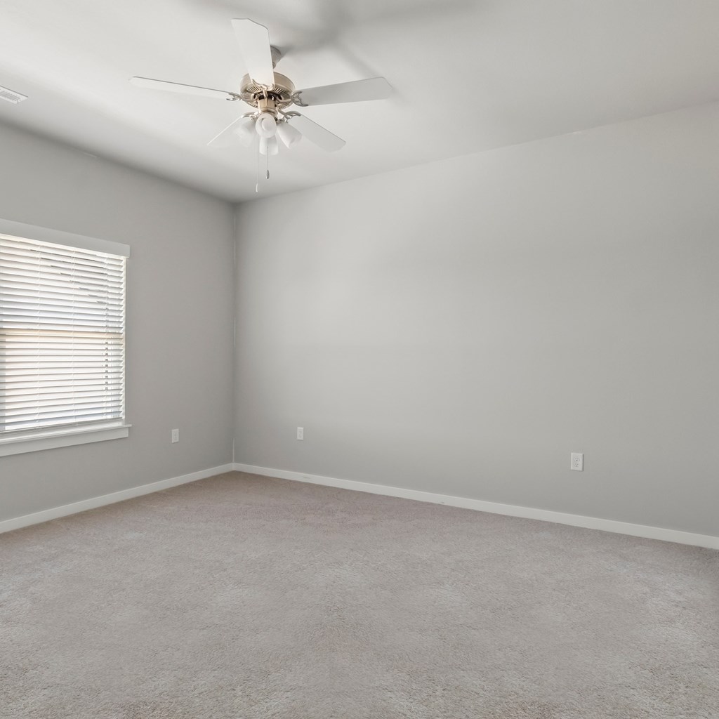 an empty room with a ceiling fan and a window at Hillcrest Village, Springdale, AR