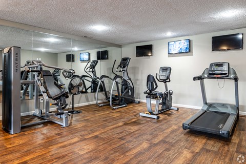 A gym with a variety of equipment including treadmills, stationary bikes, and weight machines.