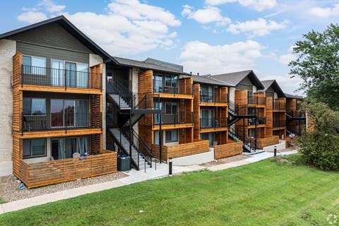 Apartment complex with wooden exteriors and black railings.