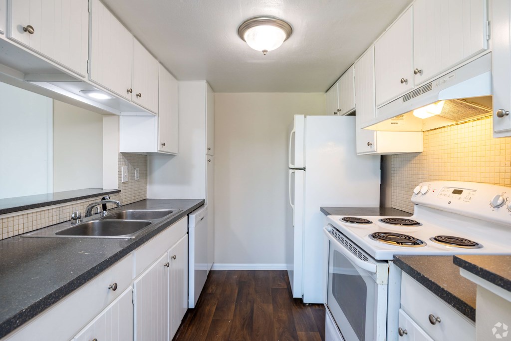 A kitchen with white cabinets and a black counter top.