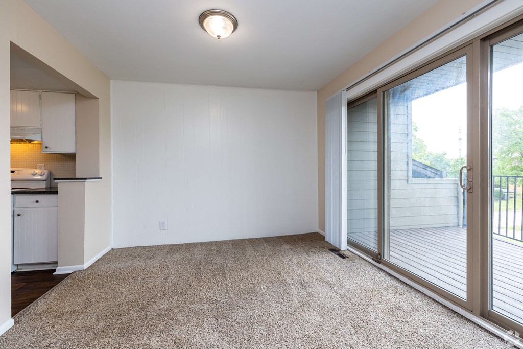 A room with a carpeted floor and sliding glass doors.