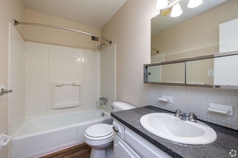 A white toilet sits next to a white bathtub in a bathroom.