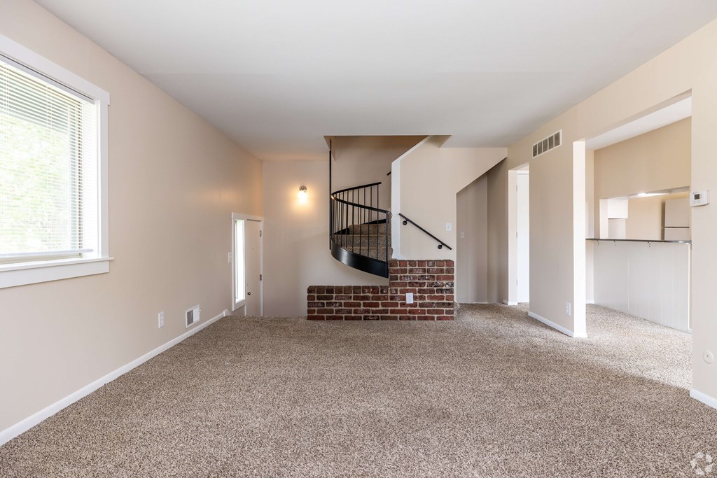 A room with a carpeted floor and a staircase with a metal railing.