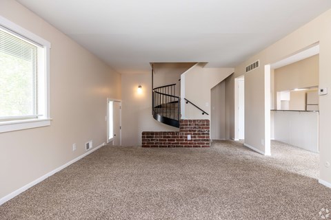 A room with a carpeted floor and a staircase with a metal railing.