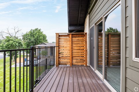 A wooden deck with a black railing and a glass door.