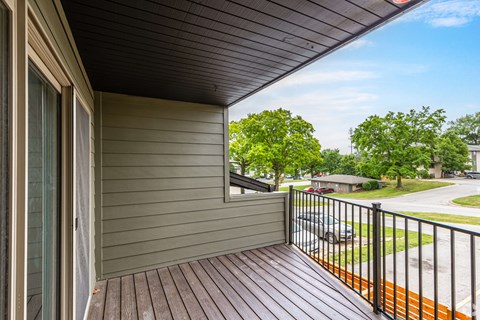 A balcony with a black railing and a brown floor.