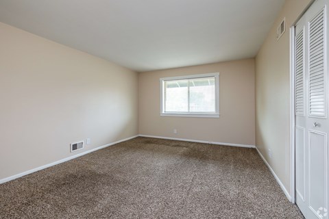 A room with a carpeted floor and a window.