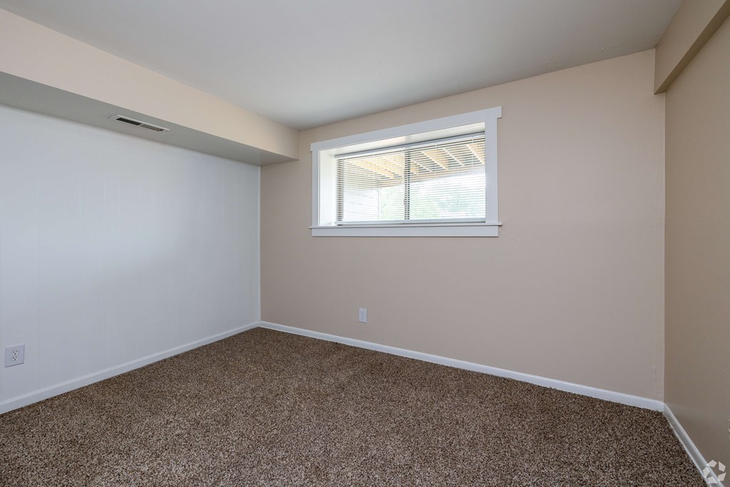 A room with a window and carpeted floor.
