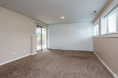 A spacious room with carpeted floor and sliding glass doors.