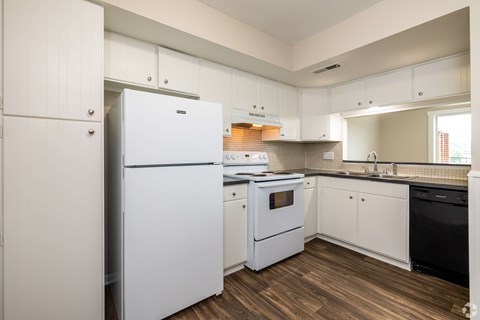 A white refrigerator is in a kitchen with wooden floors.