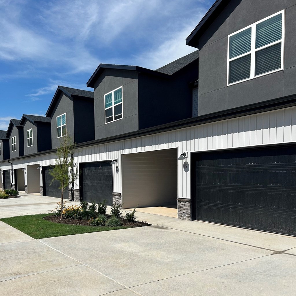 townhome with two garage doors and a sidewalk in front of it at Hillcrest Village, Springdale, 72762