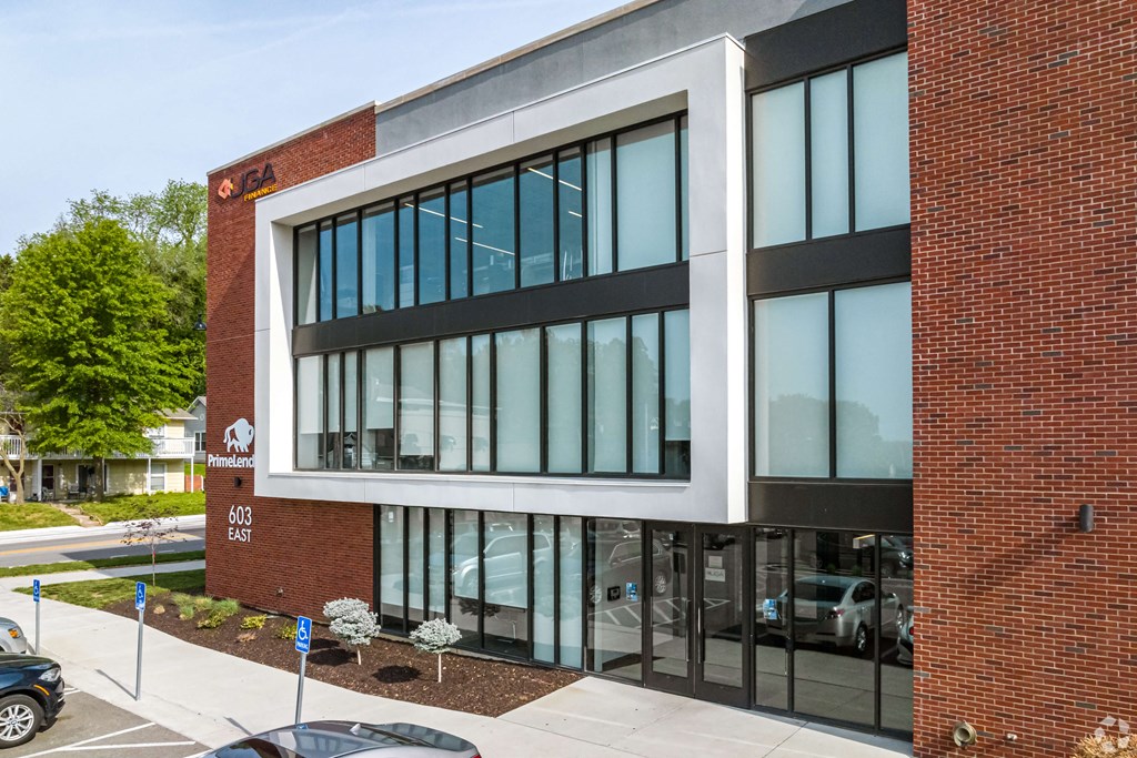 a brick building with large glass windows and a sidewalk