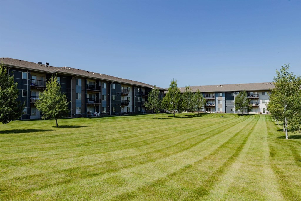 A large grassy field in front of apartment buildings.