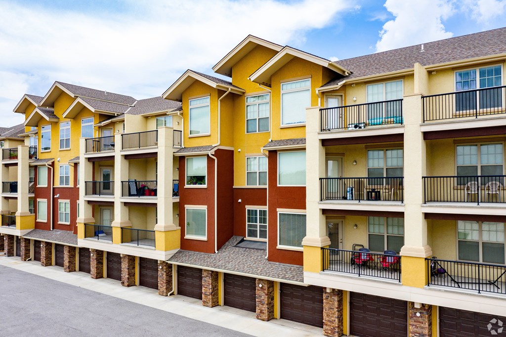 Apartment building with balconies and cars parked on the street.