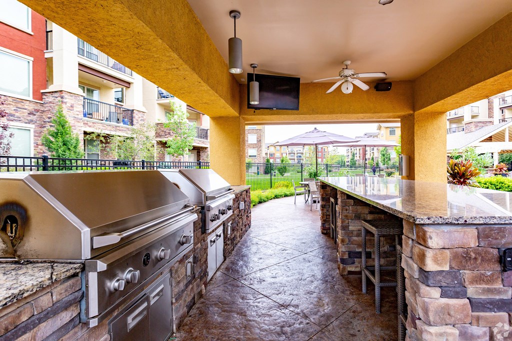 A patio with a stone wall and a grill.