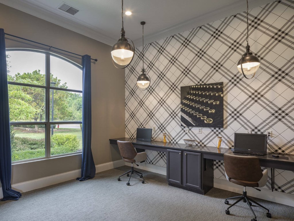 A room with a desk, chairs, and a window with curtains.