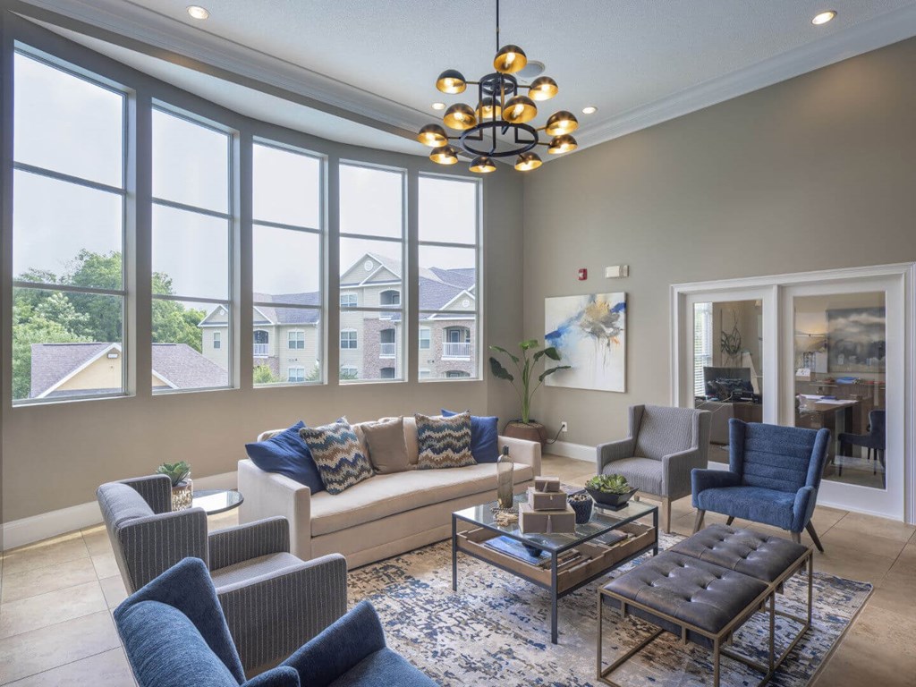 A living room with a large window and a view of houses outside.