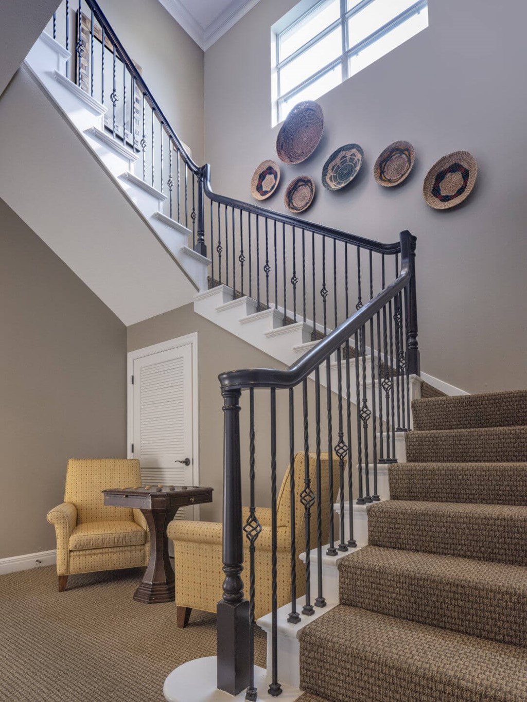 A staircase with a black railing and a yellow chair at the bottom.