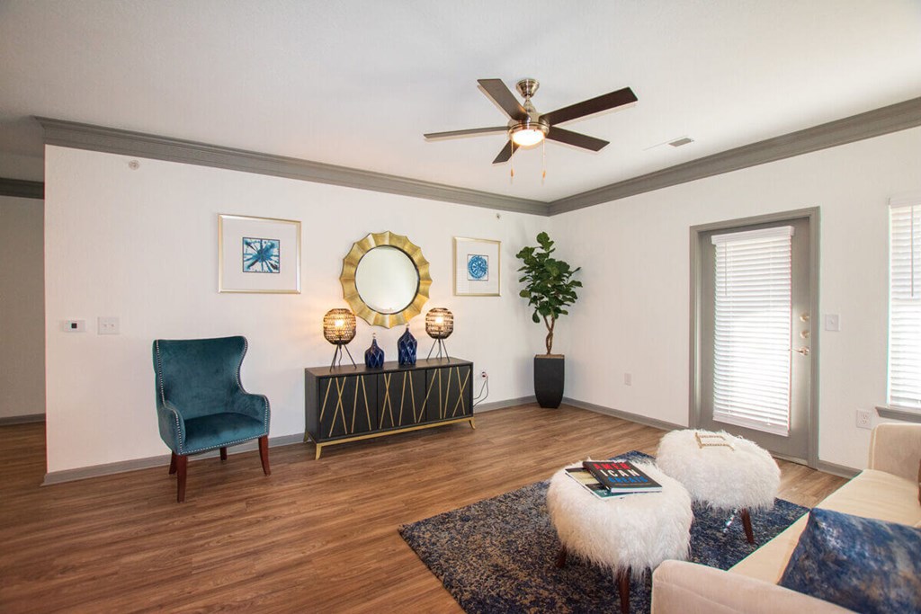 A living room with a blue chair and a mirror.