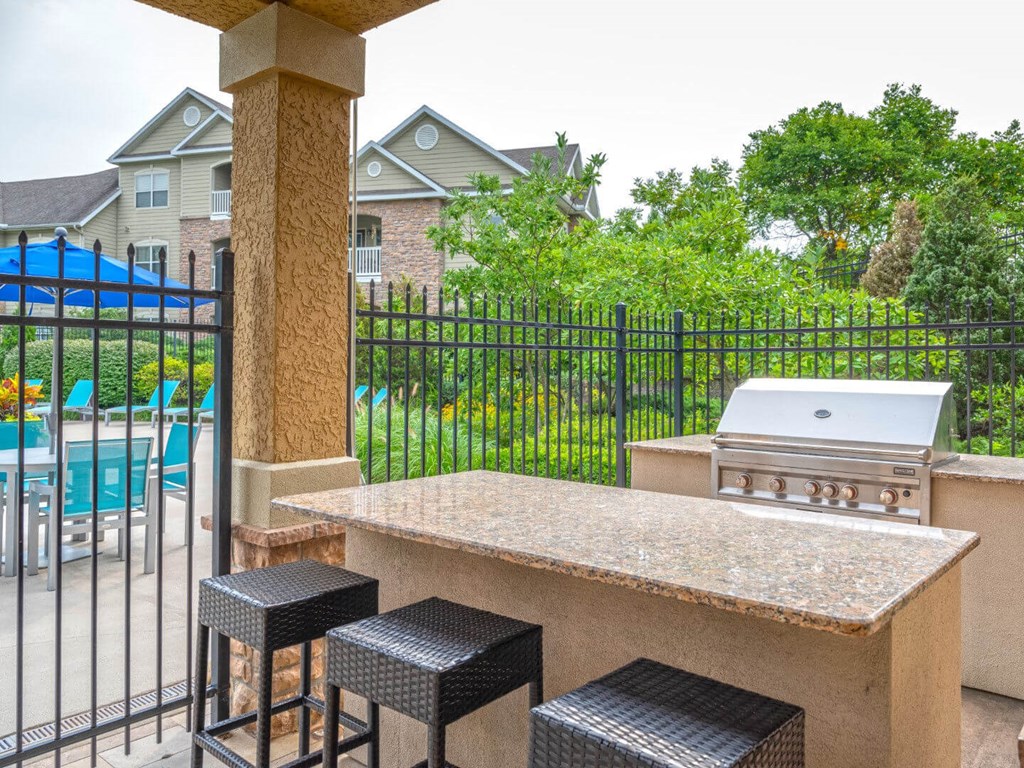 A black metal fence surrounds a concrete bar area with two black stools.