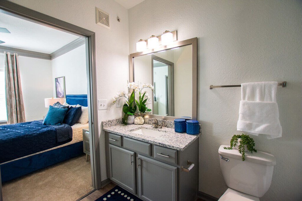 A bathroom with a blue bed and a white toilet.