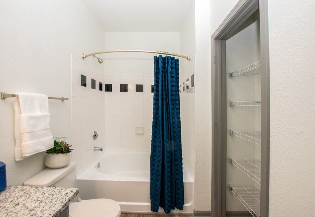 A small bathroom with a white tub and a blue shower curtain.