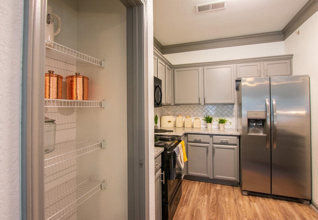 A kitchen with a refrigerator, oven, and a stove.