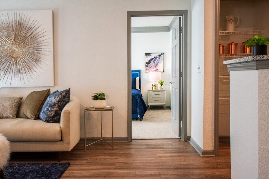 A living room with a beige couch and a large painting on the wall.