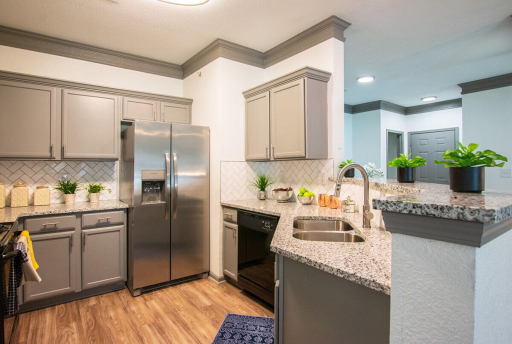 A kitchen with a stainless steel refrigerator and a marble countertop.