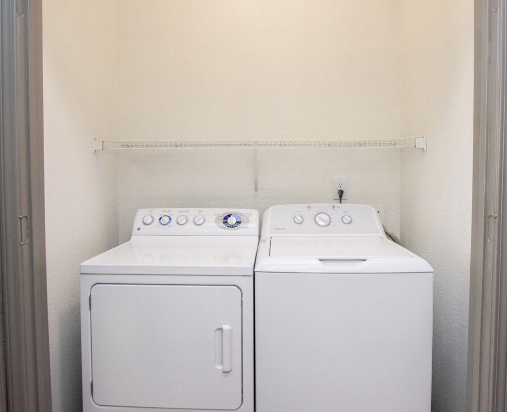 Two white front loading washing machines in a small laundry room.