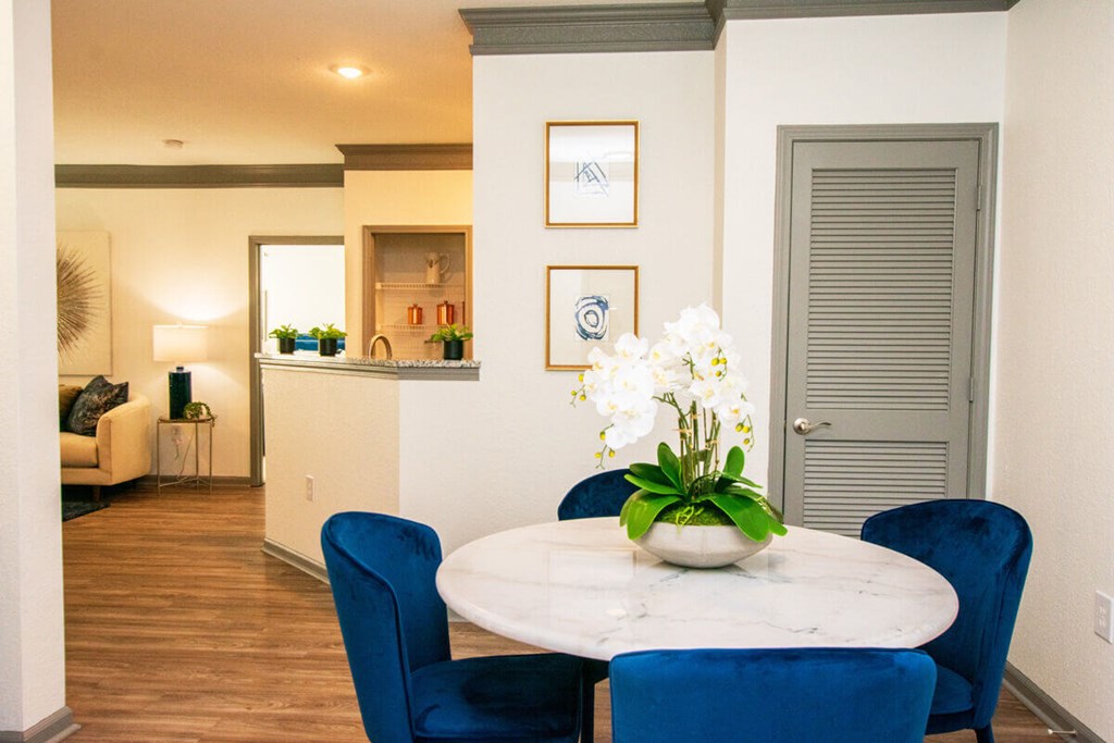 A dining room with a round table and blue chairs.