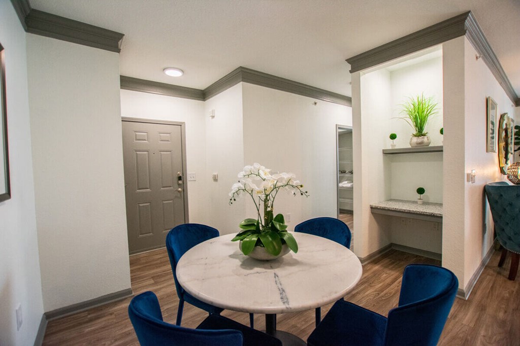 A dining room with a round table and blue chairs.