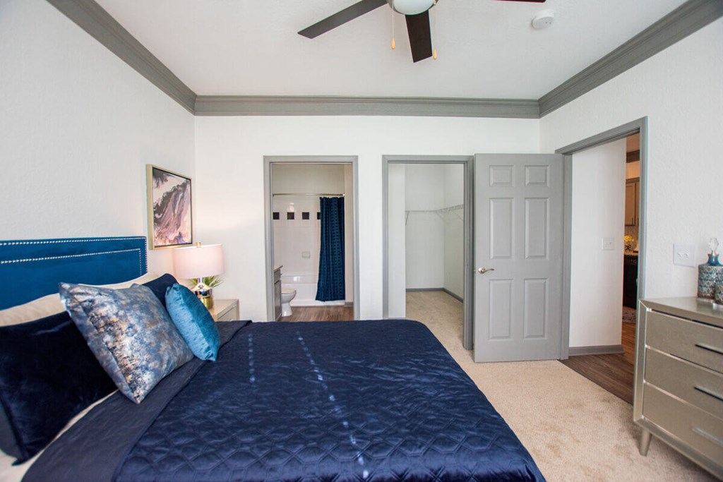 A bedroom with a bed, dresser, and ceiling fan.