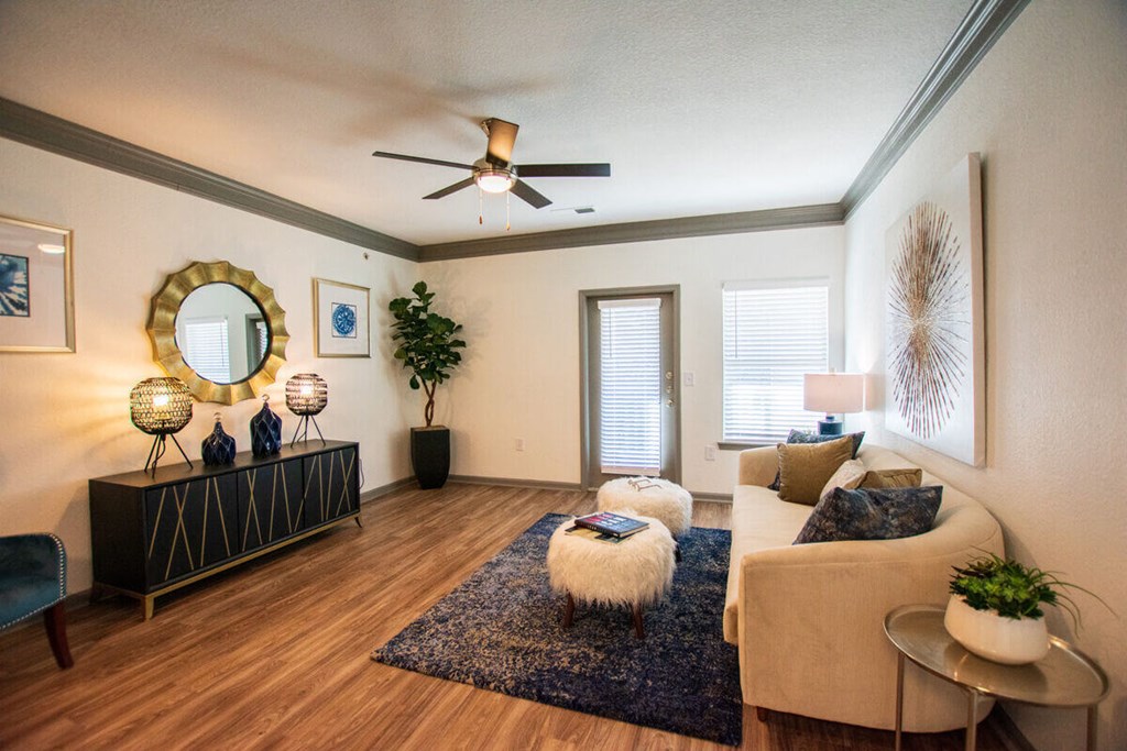 A living room with a ceiling fan and a rug on the floor.